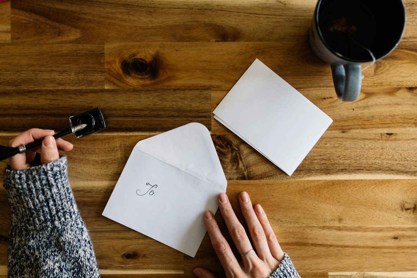Hands with envelopes and paper on a wooden table
