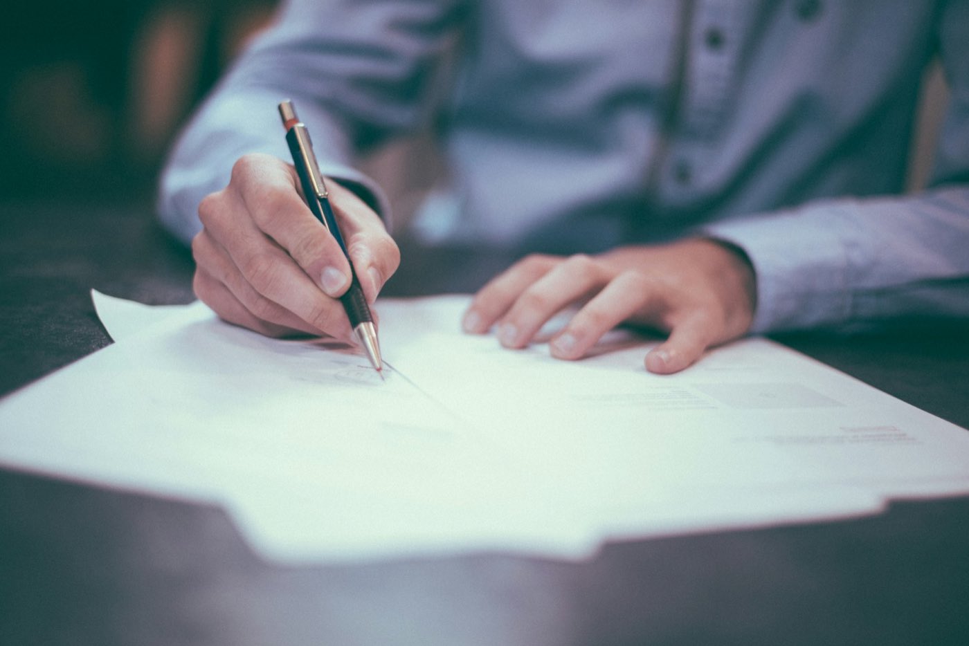 A hand writing a letter with a pen